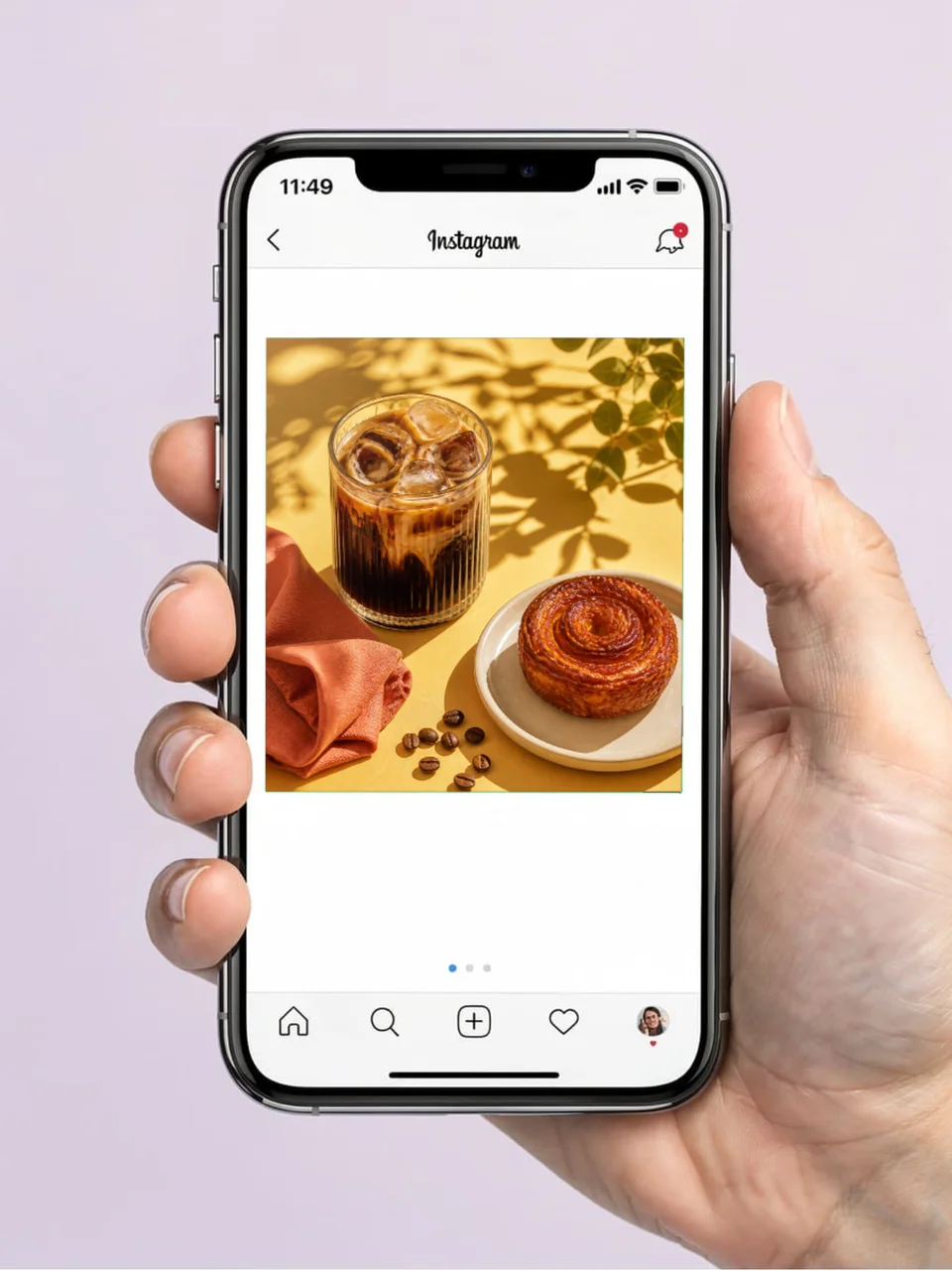 Photorealistic Instagram café post mockup shown on an iPhone held in one hand against a soft lavender background